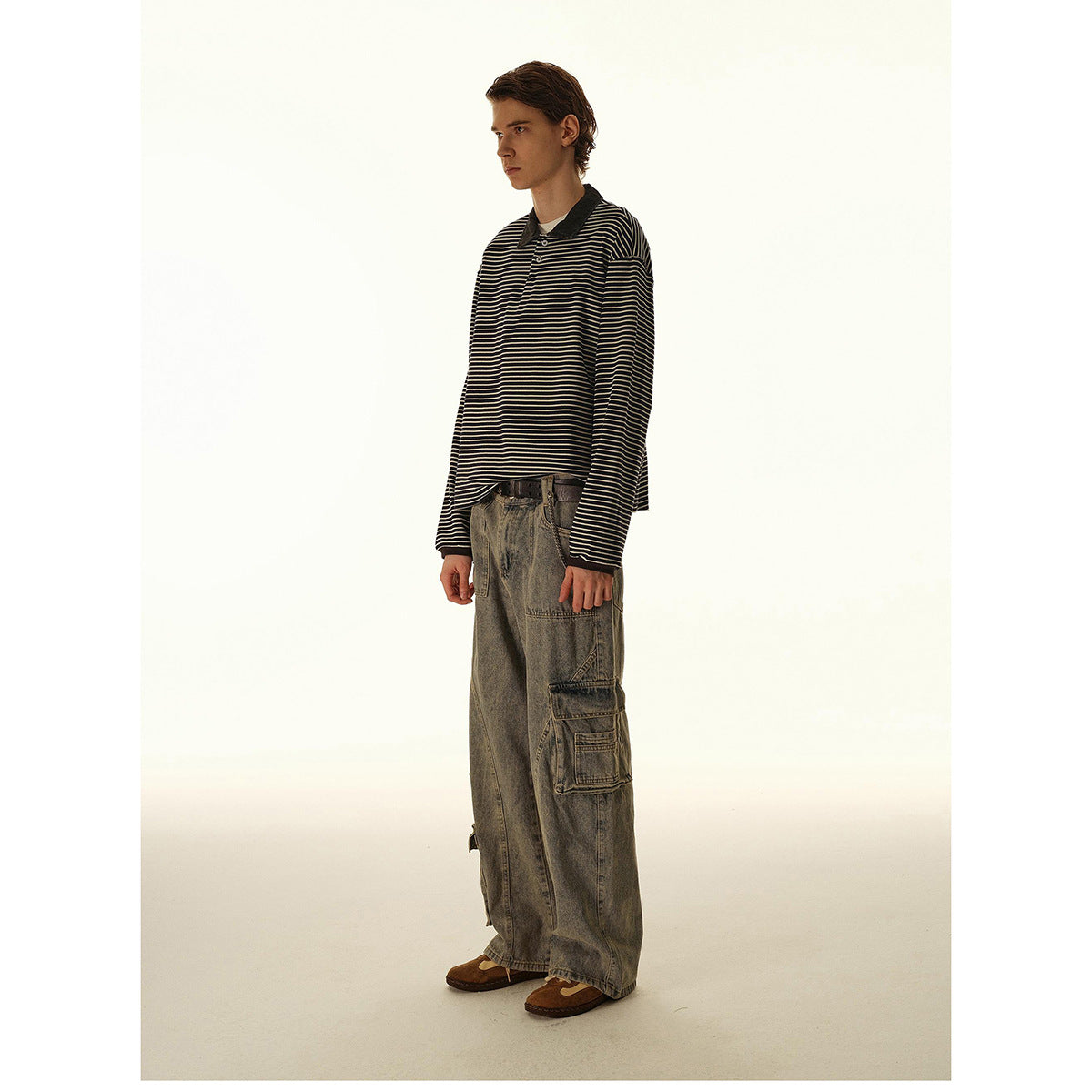 Side view of a model in a black-and-cream striped long-sleeve polo and loose gray cargo jeans.