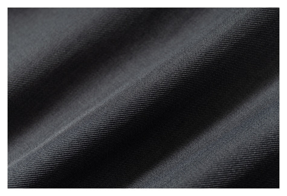 Macro view of dark charcoal fabric with a fine diagonal weave and soft folds.