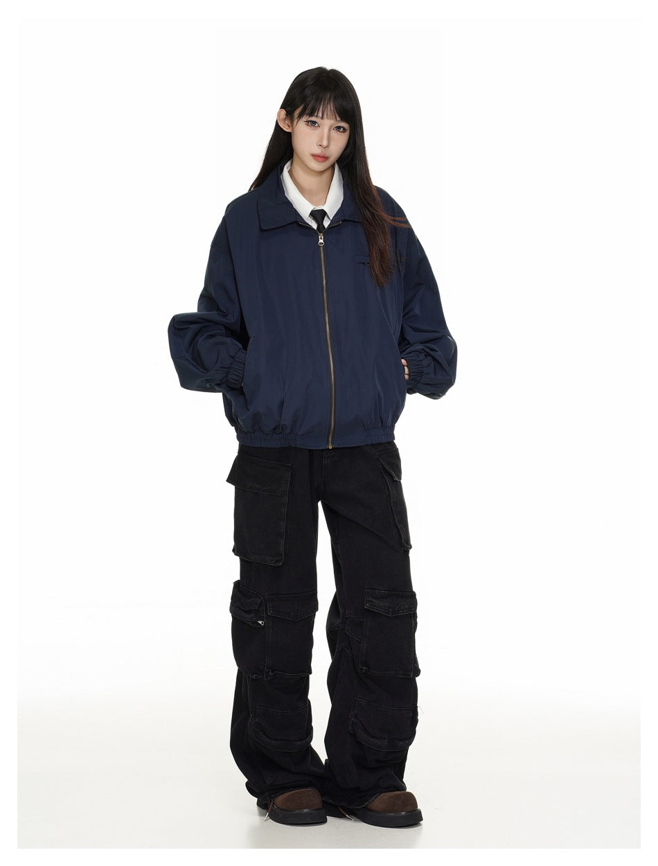 Full-length front view of a model wearing a zipped navy jacket with black cargo pants and brown shoes.