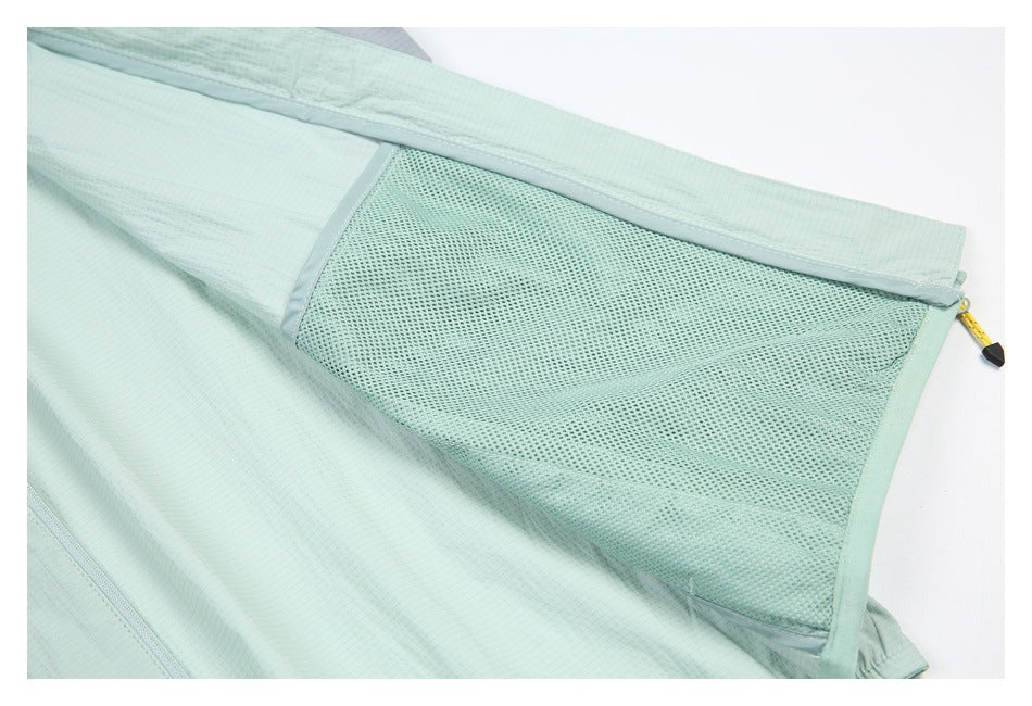Close-up of a pale mint garment with a large mesh panel and a yellow zipper pull.
