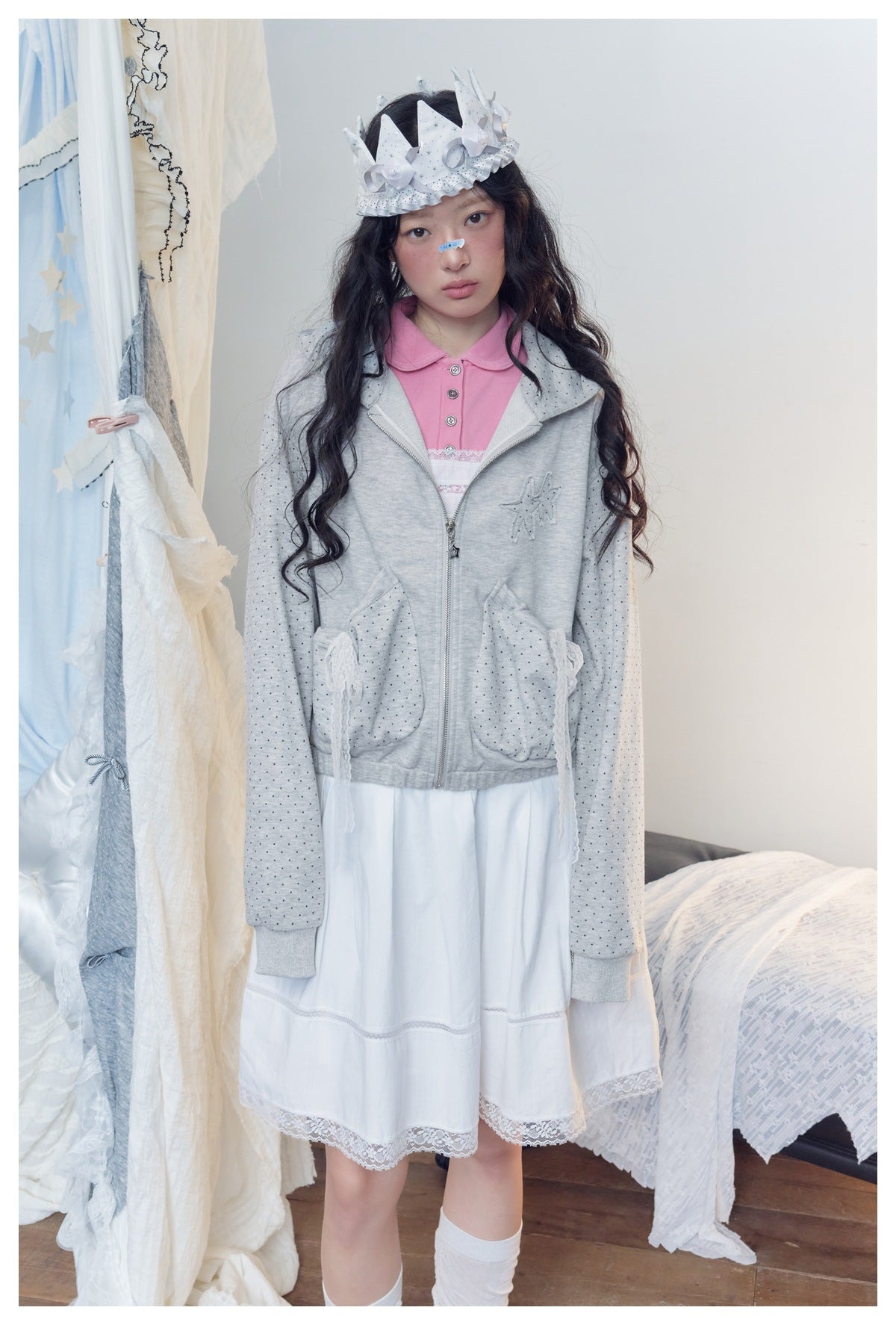 Front view of a model wearing a light gray dotted zip hoodie with lace-trim pockets over a white dress.