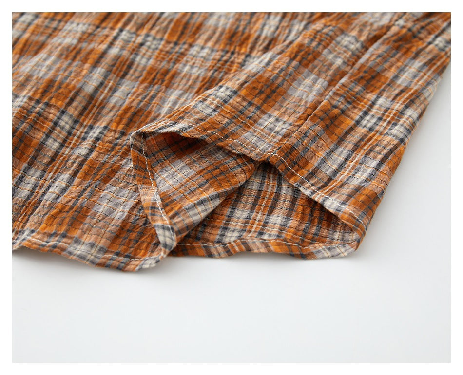 Close-up of a side opening and stitched edge on orange, gray, and cream plaid fabric.
