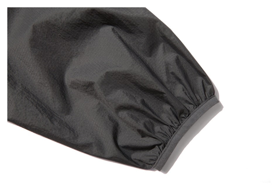 Close-up of a gathered dark charcoal sleeve cuff finished with a narrow band.