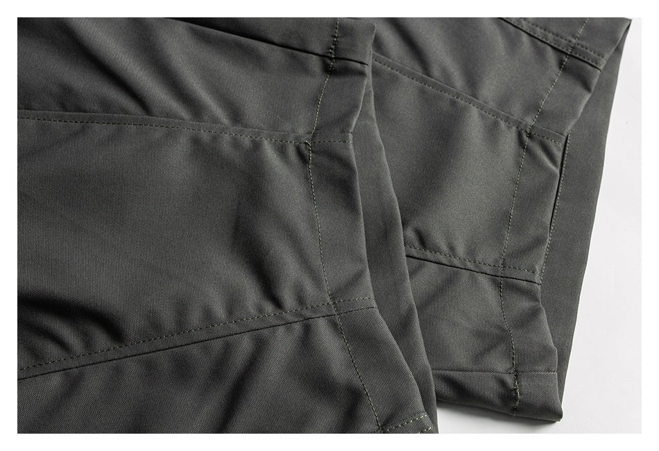 Close-up of charcoal trouser legs showing panel seams, stitching, and finished hems.