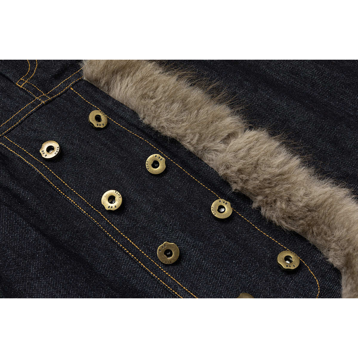 Close-up of dark denim with brass-tone buttons and a wide strip of taupe faux-fur lining.