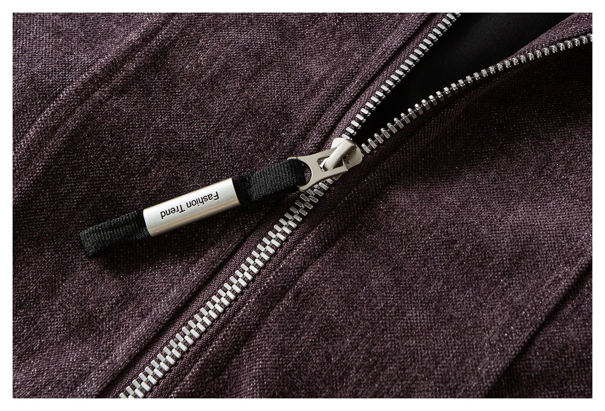 Close-up of the silver zipper and black pull tab on plum textured fabric.