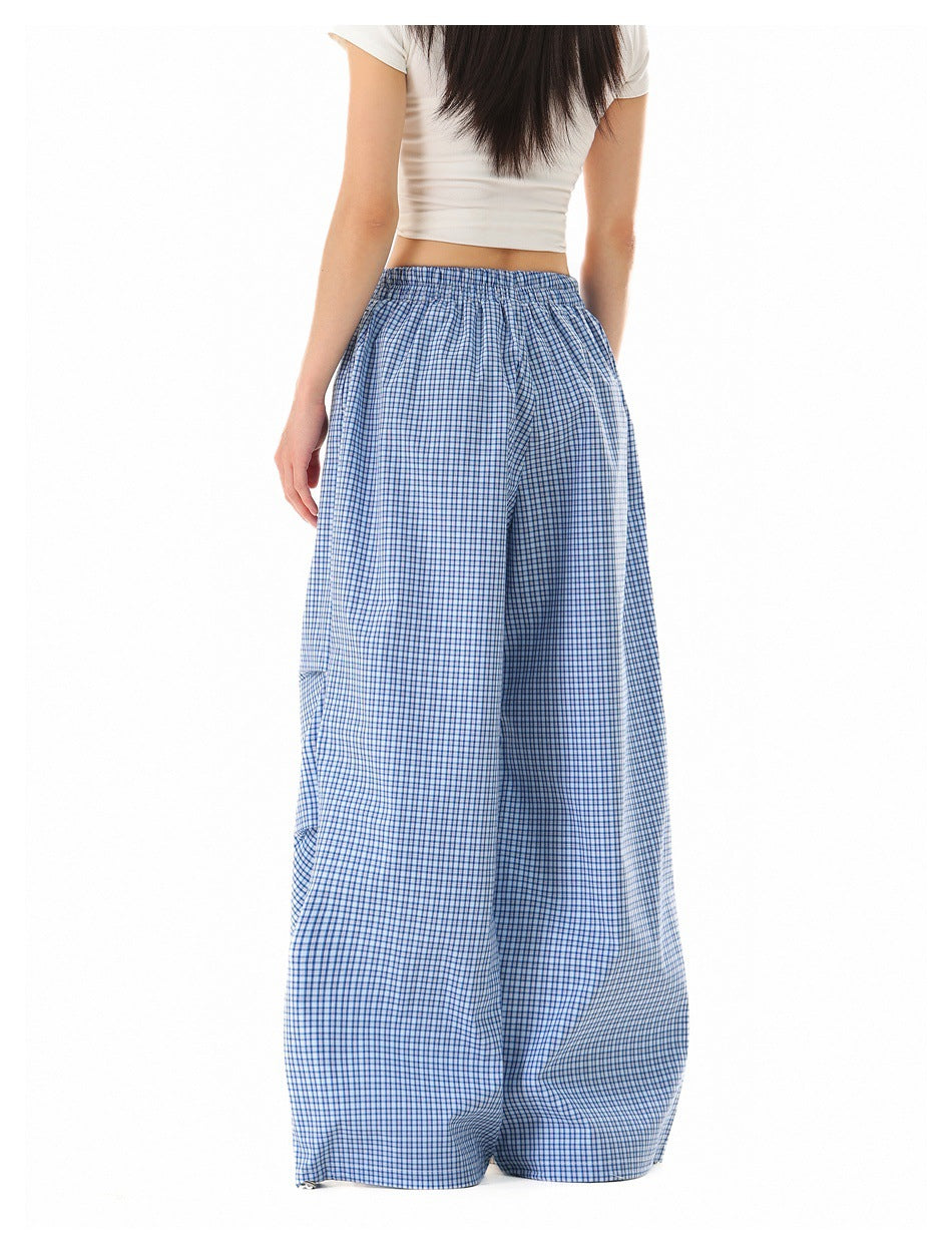 Back view of a model wearing loose blue-and-white check pants with an elastic waist.