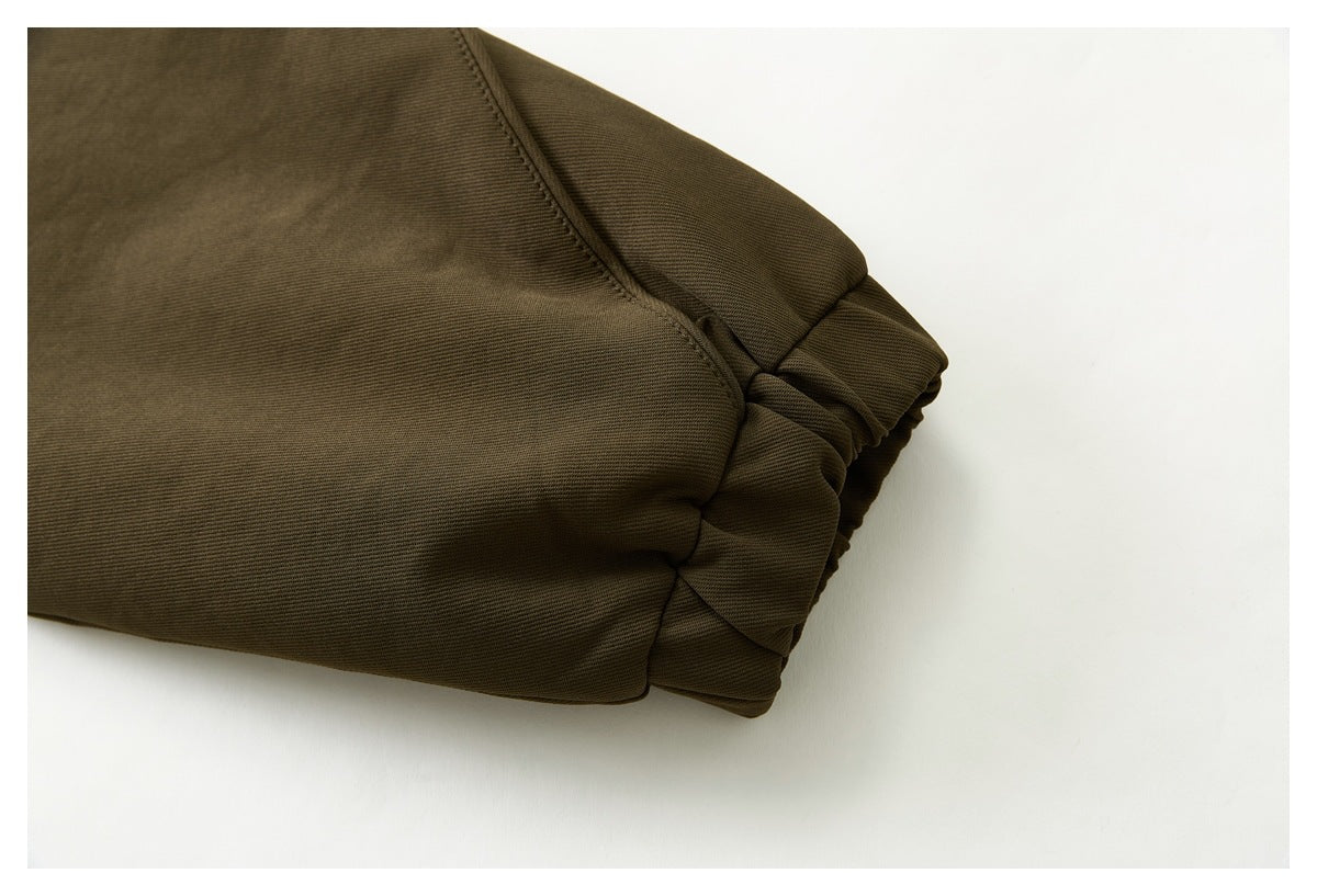 Close-up of the olive-brown jacket's gathered elastic sleeve cuff and seam.