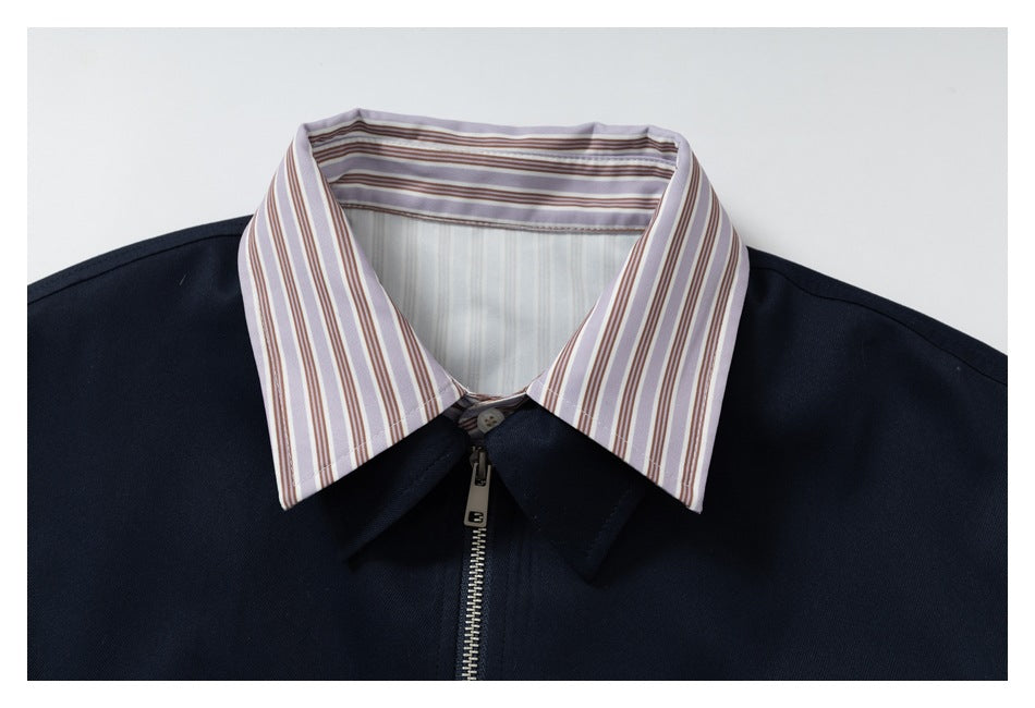 Close-up of a navy zip-front jacket with a pointed collar and lavender, brown, and white striped lining.