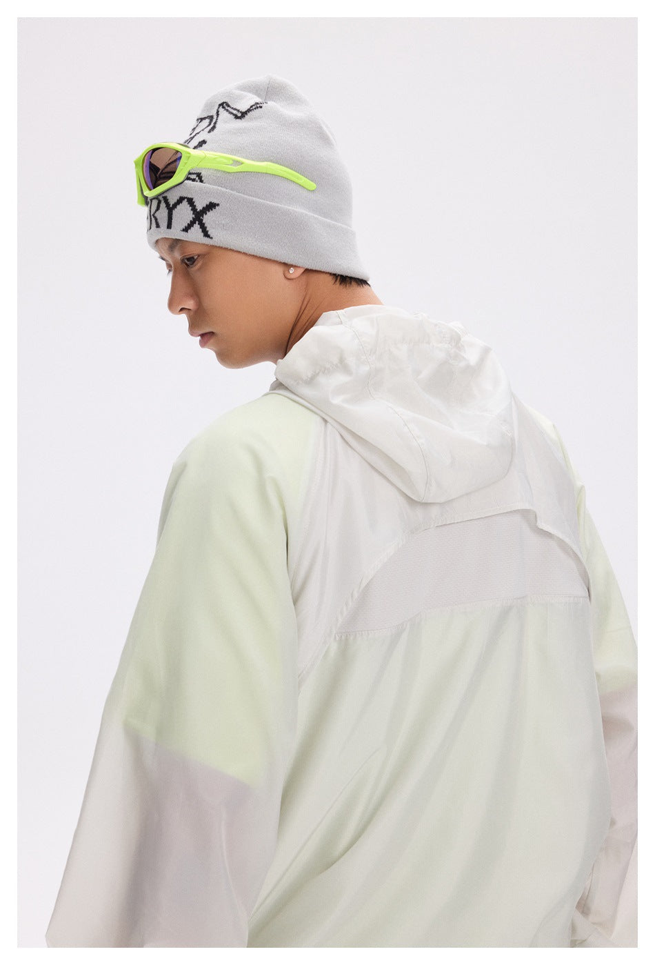 Model in a pale mint and white hooded jacket, shown from behind with the hood down.