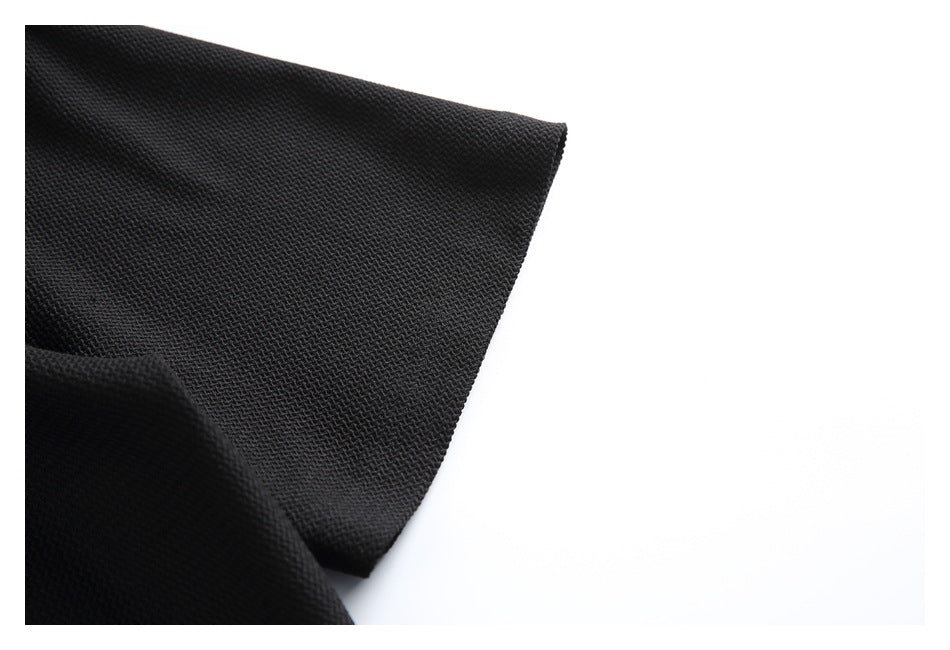 Close-up of a black garment sleeve edge showing its textured surface and hem against a white background.