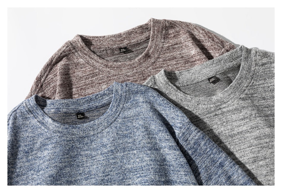Close-up of three marled crewneck shirts in blue, gray, and brown, with neck labels visible.