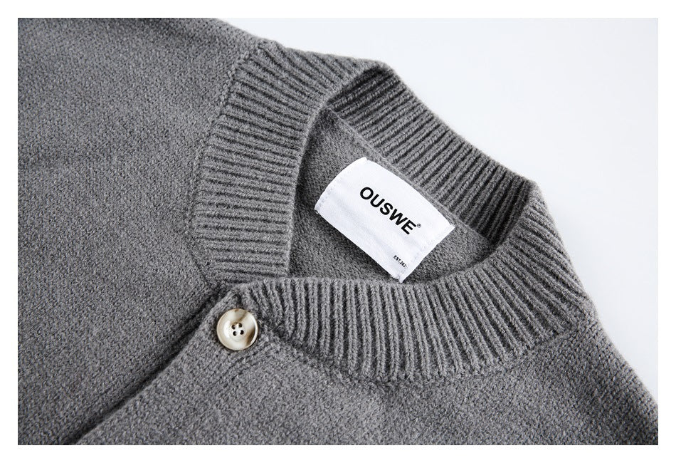 Close-up of a charcoal gray knit cardigan’s ribbed neckline, top button, and sewn-in neck label.