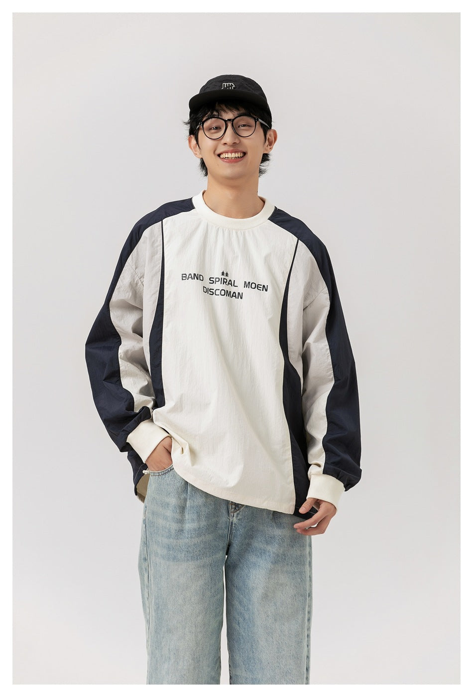 Front view of a smiling model in an ivory long-sleeve top with navy panels and black chest lettering.