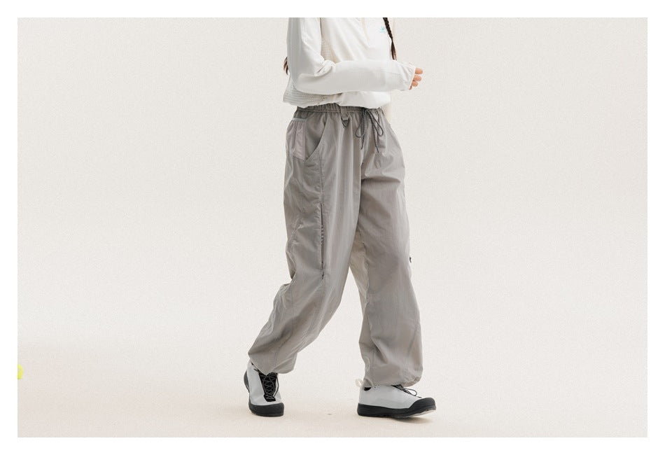 Cropped model wearing loose gray drawstring pants, shown in a walking side-front view.