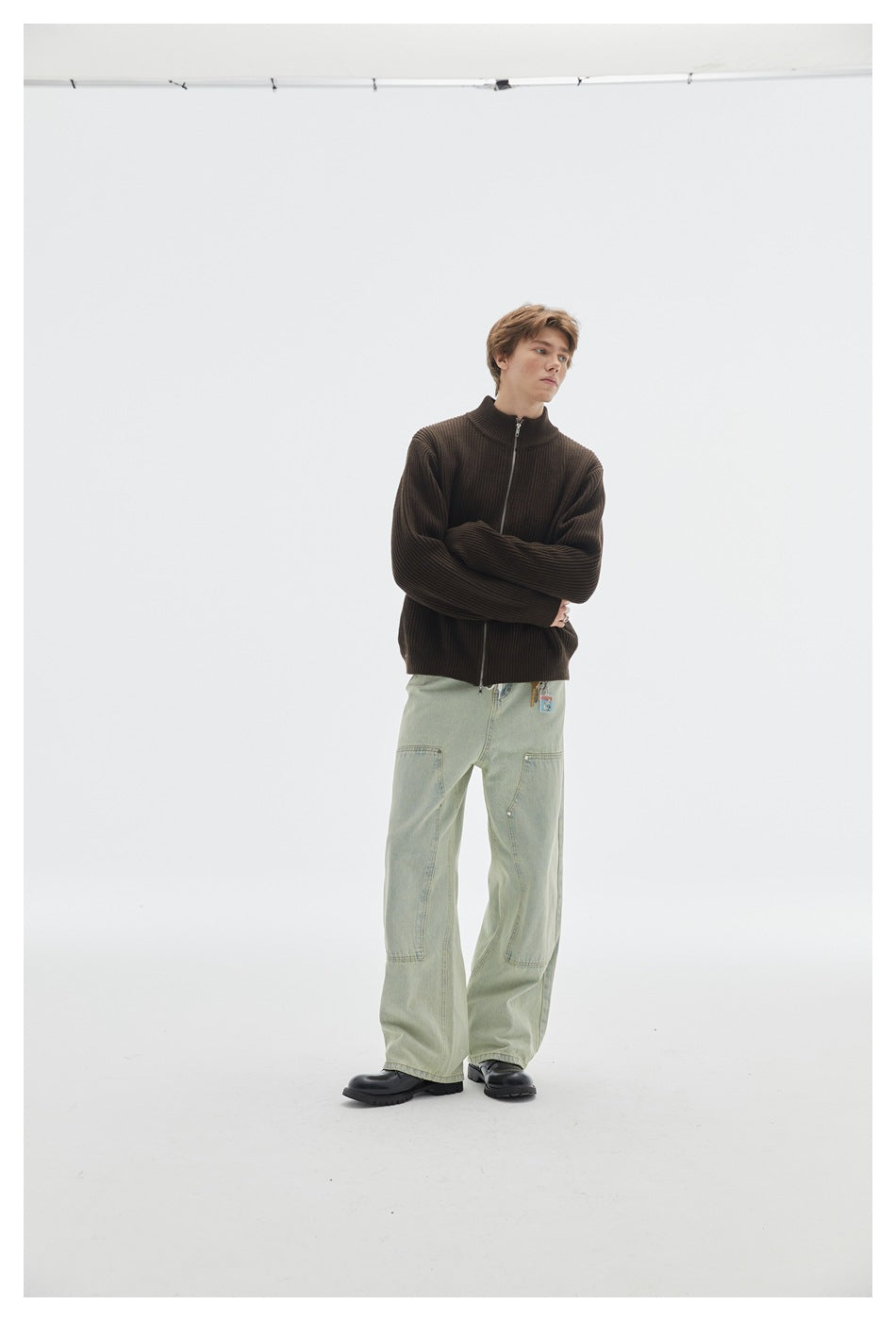 Model wearing brown ribbed zip-front sweater with light green wide-leg pants, arms crossed