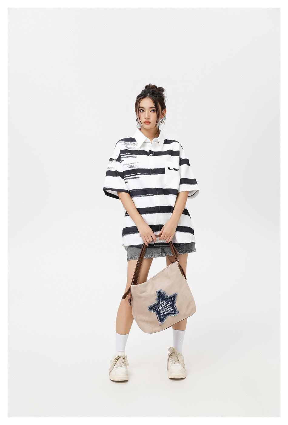 Model wearing a white oversized short-sleeve shirt with black brushstroke stripes and a chest pocket, with a gray denim