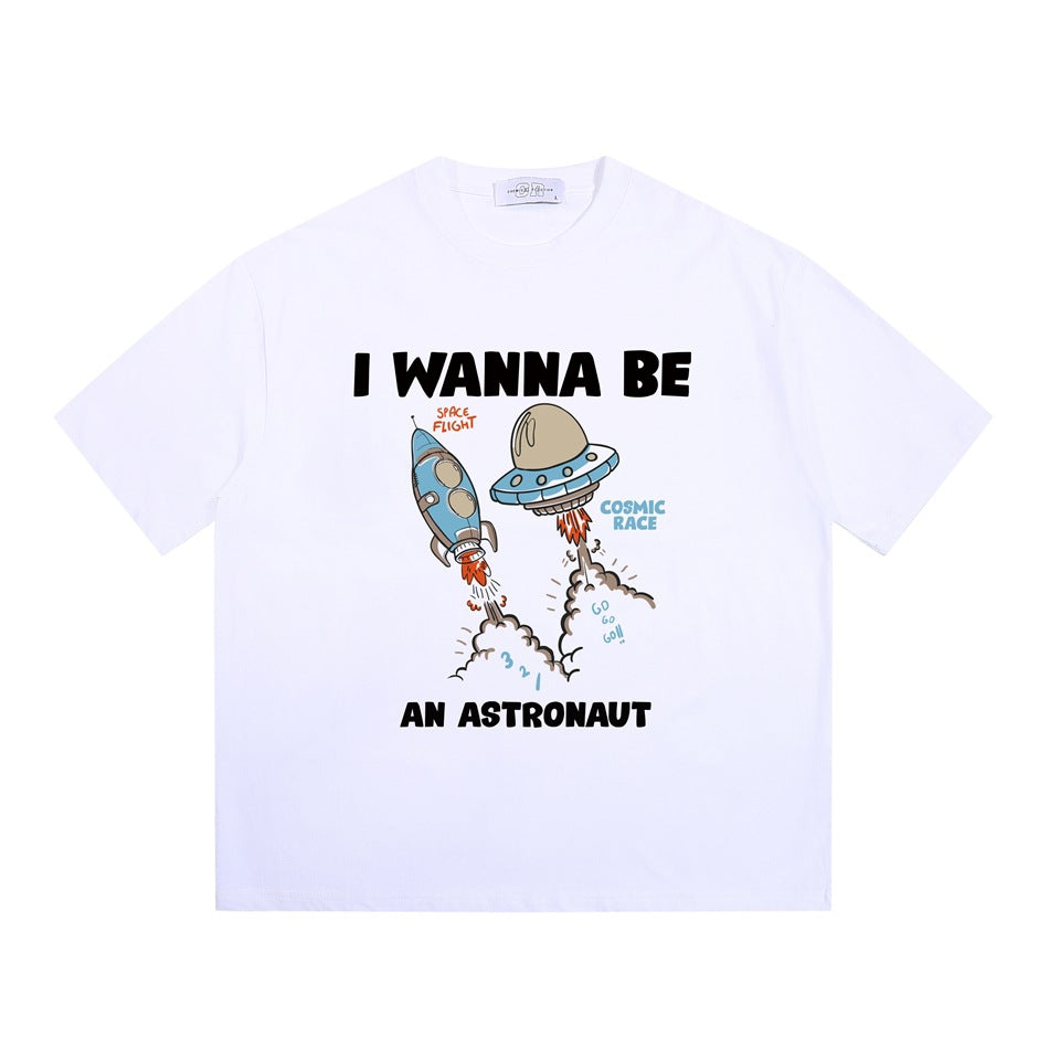 White short-sleeve crew-neck T-shirt with cartoon rocket and UFO 'I WANNA BE AN ASTRONAUT' graphic, flat lay