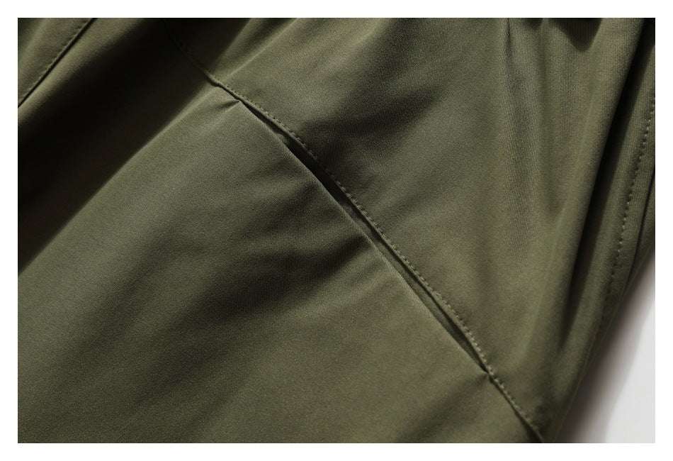Close-up of olive-green pants with a curved stitched seam and an adjacent vertical edge seam.