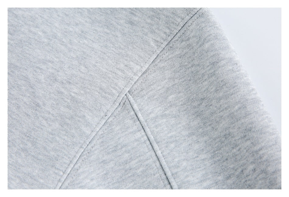 Close-up of a stitched sleeve seam on a light gray heathered garment.