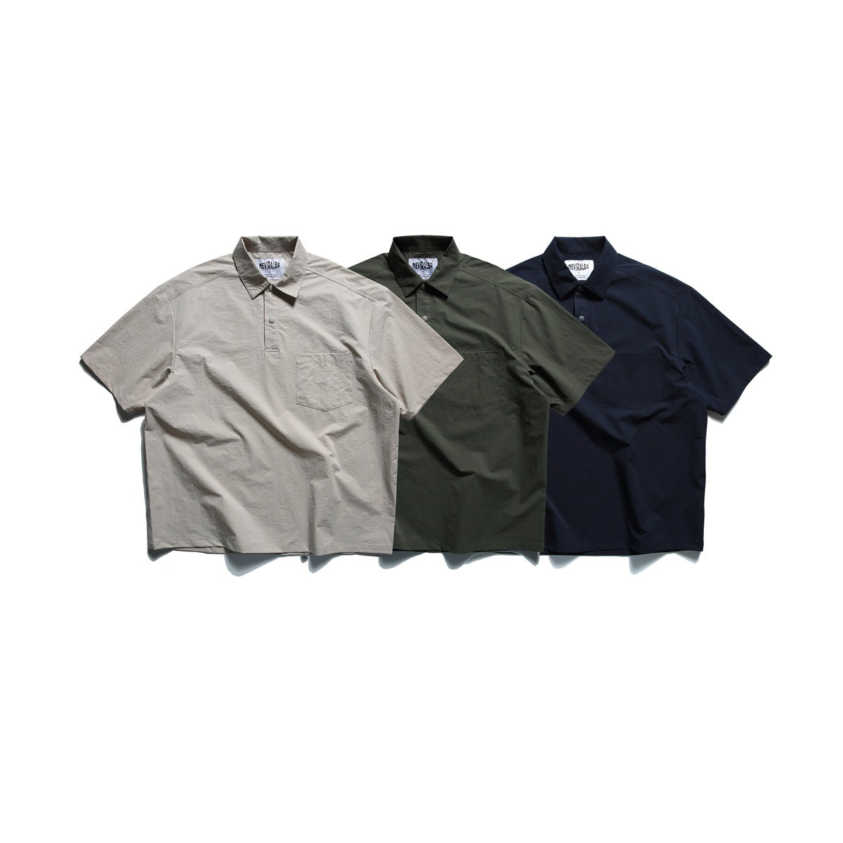 Three short-sleeve collared shirts with snap plackets and chest pockets in taupe, dark olive and navy.