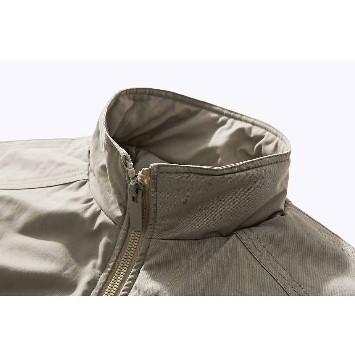 Close-up of a light beige jacket's raised collar, zipper, and stitched seams.