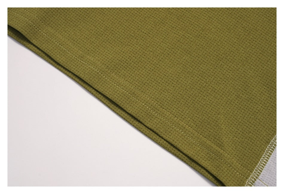 Close-up of an olive-green garment hem with double stitching and part of a white contrast panel.
