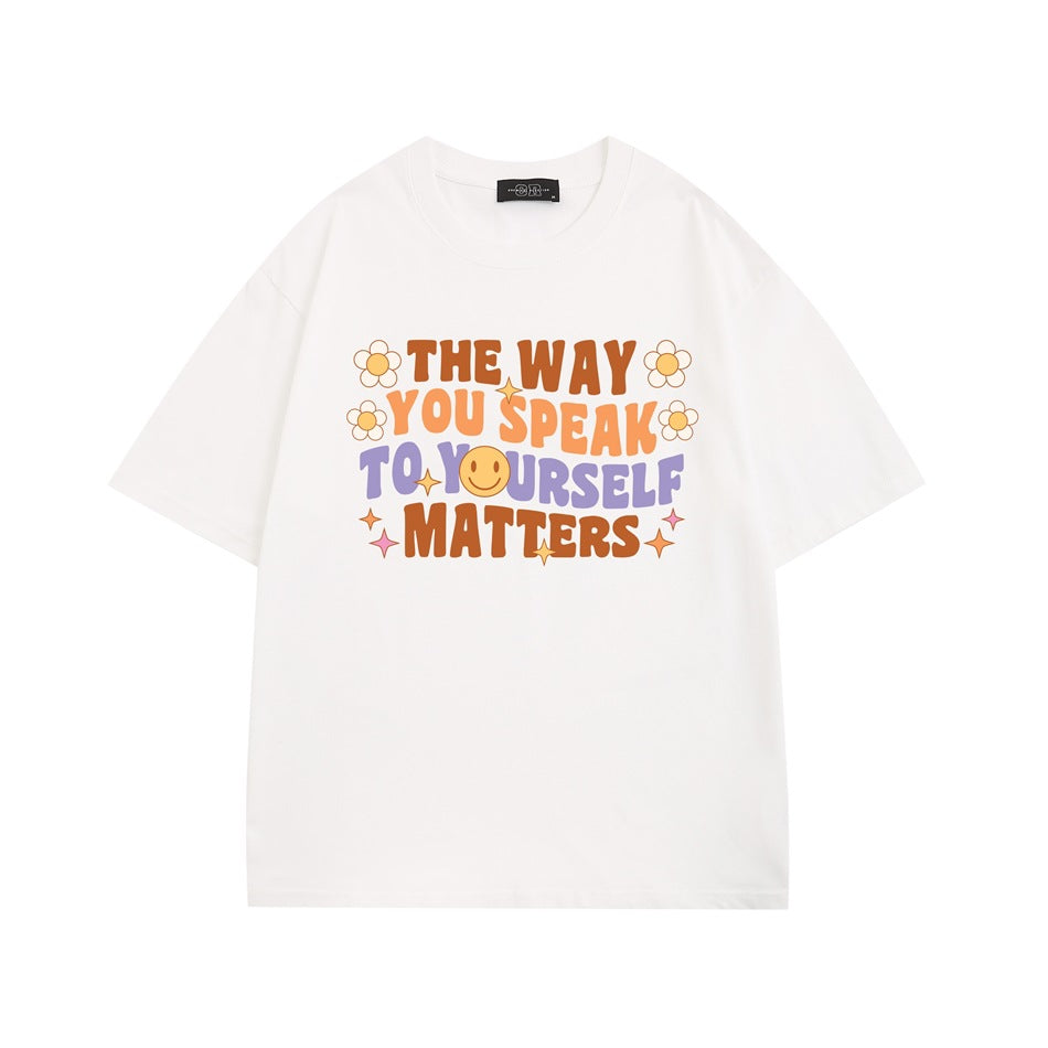 White short-sleeve T-shirt with colorful retro slogan print, daisies and smiley face on the chest