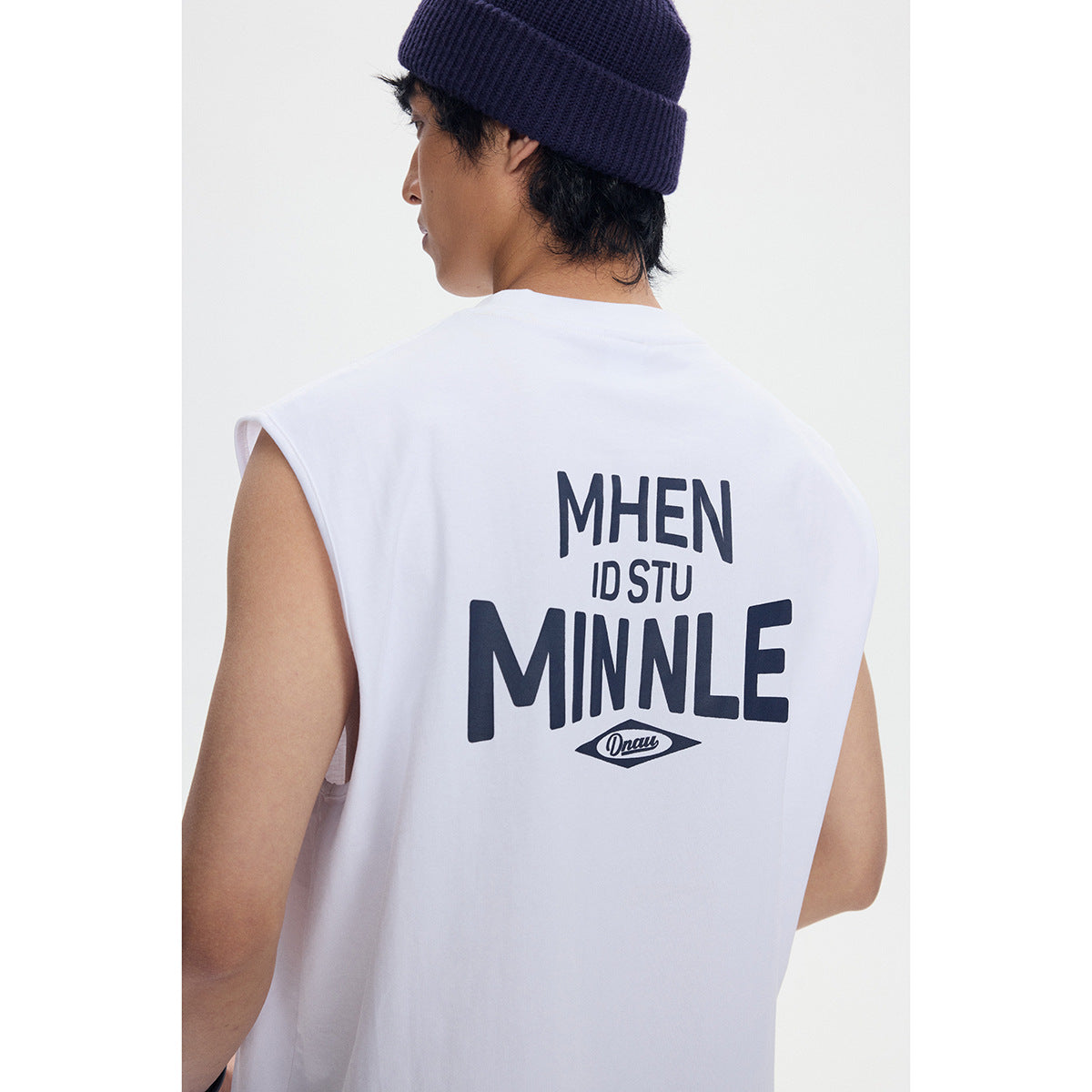 Back view of a model wearing a white sleeveless tee with a large dark graphic across the back.