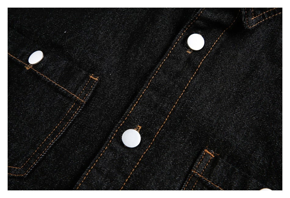 Close-up of a black denim shirt placket and pocket edges with silver snaps and orange stitching.