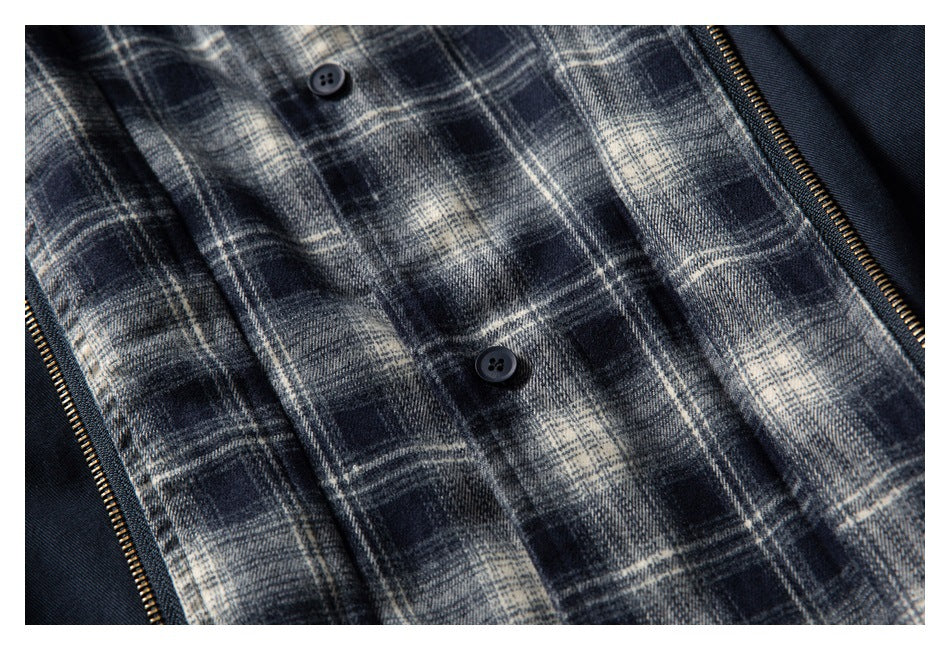 Close-up of a navy, gray, and cream plaid lining with black buttons and a brass-tone zipper.