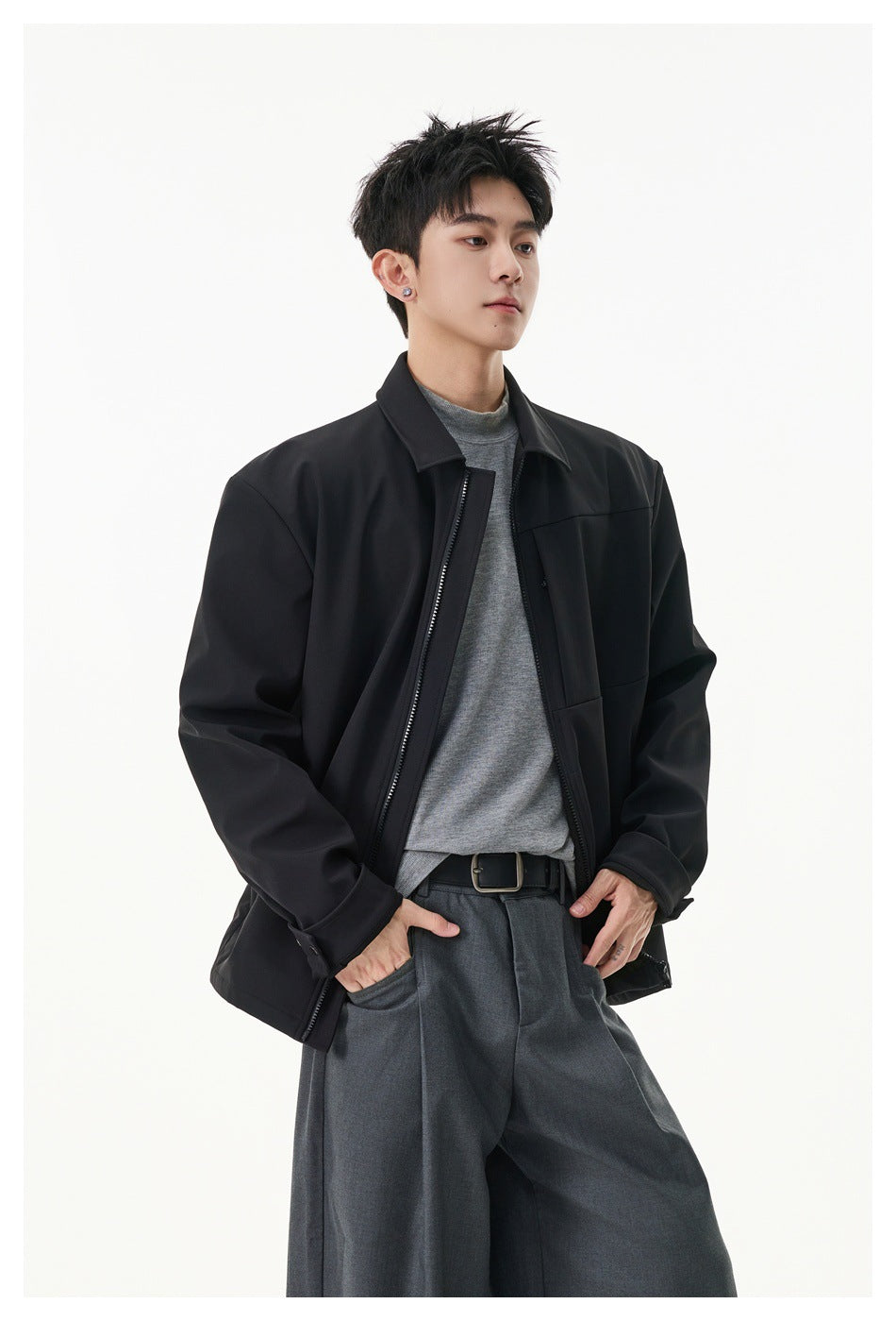 Model wearing an open black zip-front jacket with a pointed collar and buttoned cuffs.