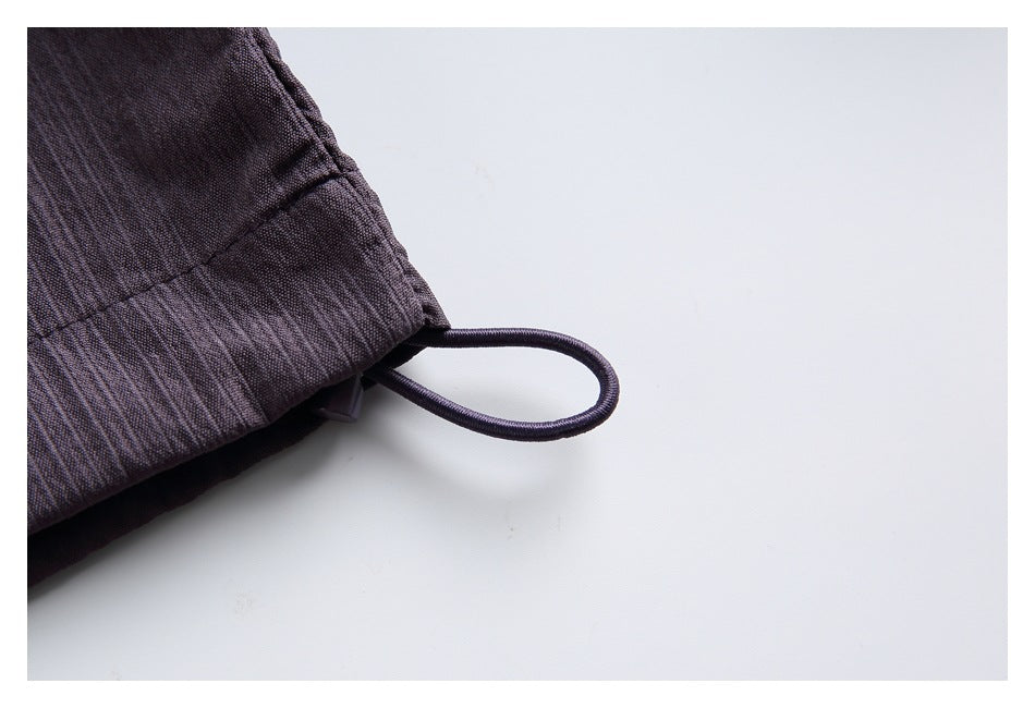 Close-up of a dark charcoal-purple garment edge with a small fabric loop against a white background.