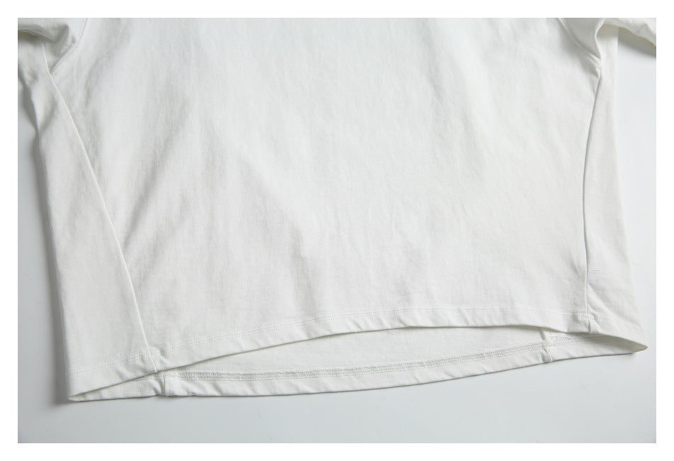 Close-up of the white T-shirt's curved hem, stitching, and side seams.