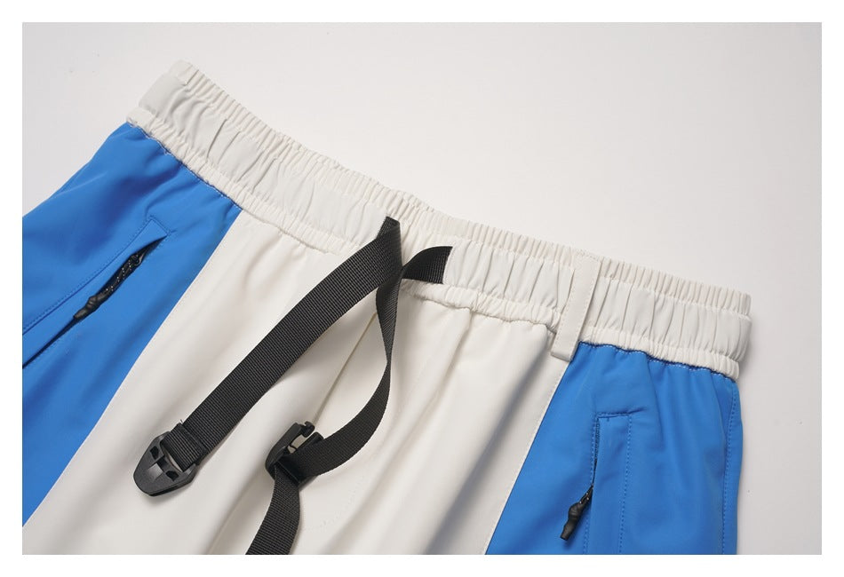 Close-up of blue-and-white pants showing the elastic waistband, black adjustable webbing belt and zip pockets.