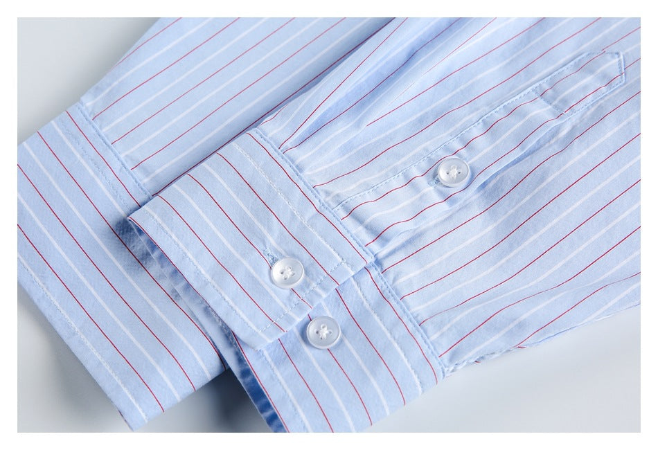 Close-up of a light blue striped shirt cuff and sleeve placket with white buttons.