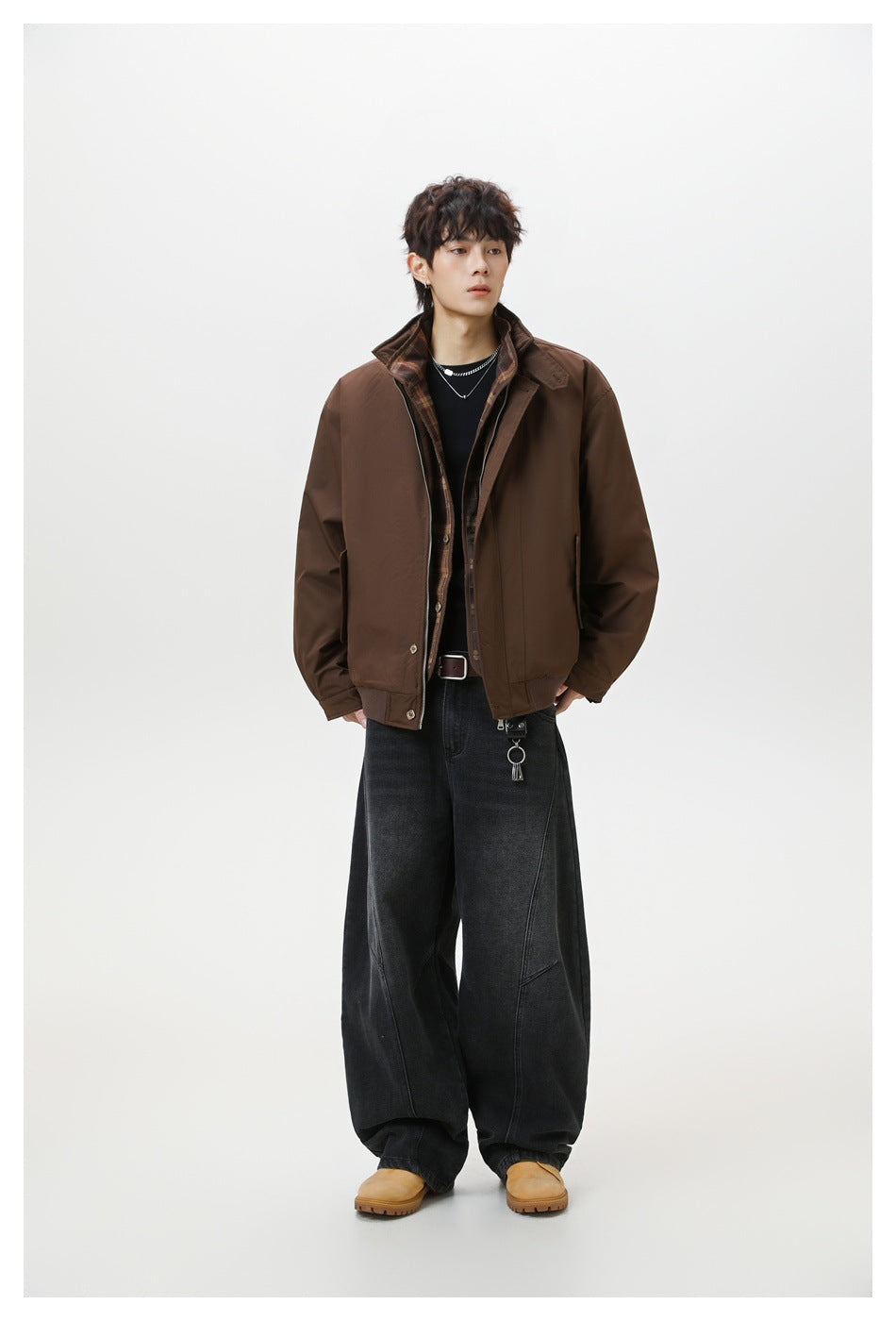 Full-length model wearing a brown zip-front jacket with a plaid inner collar and oversized black jeans.