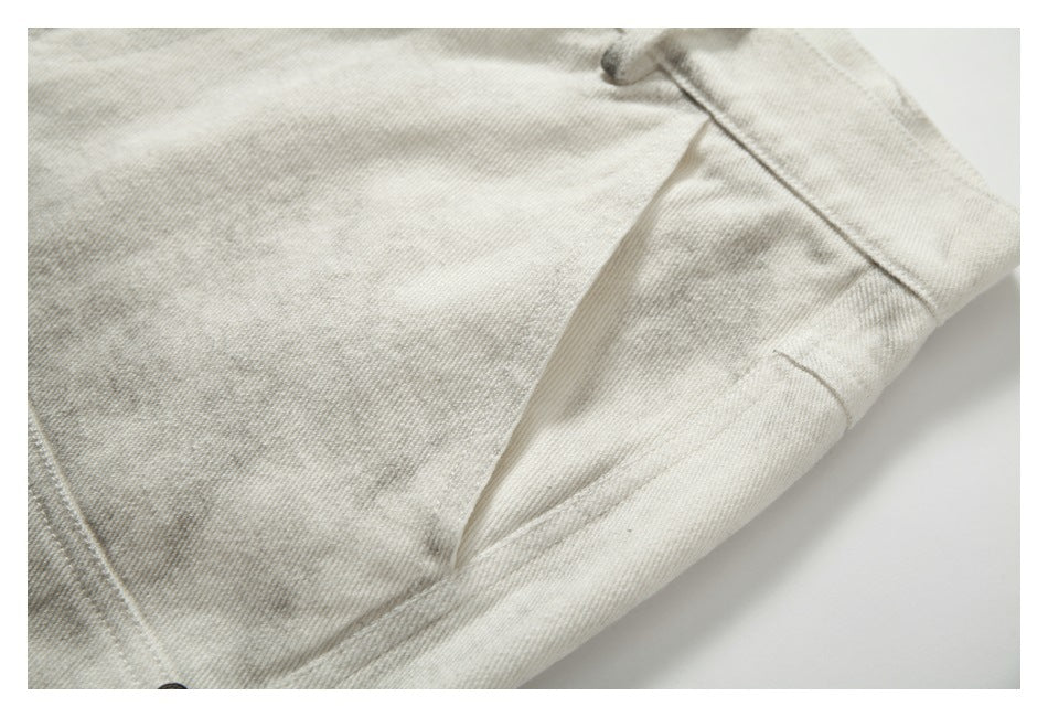 Close-up of cream-gray mottled trousers showing diagonal seams and a folded fabric edge.