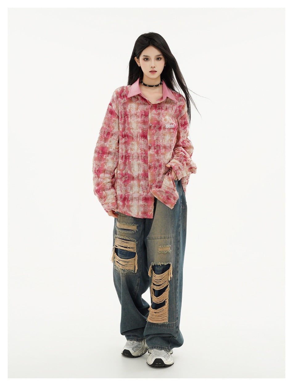 Full-length model wearing an oversized pink and beige abstract-print button-up shirt with distressed blue jeans.