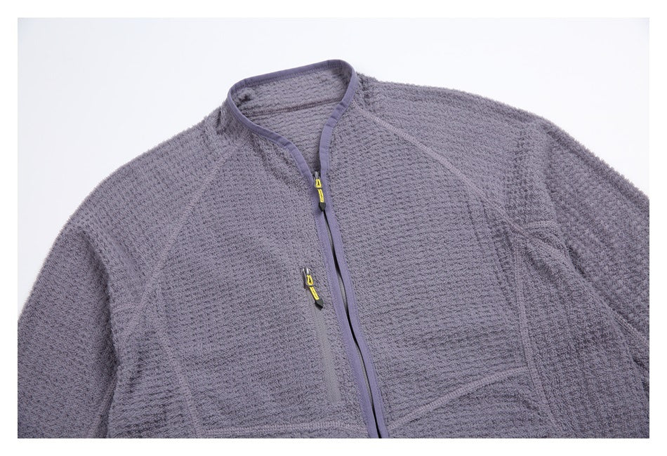 Close view of a lavender-gray jacket front with a stand collar, yellow zipper pulls, and textured fabric.