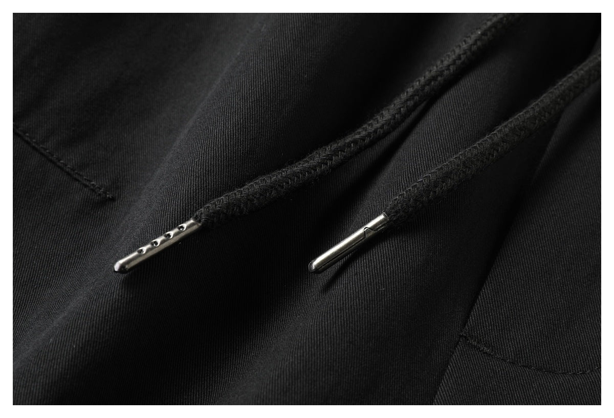 Close-up of black pants' drawstrings with metal tips against the fabric.