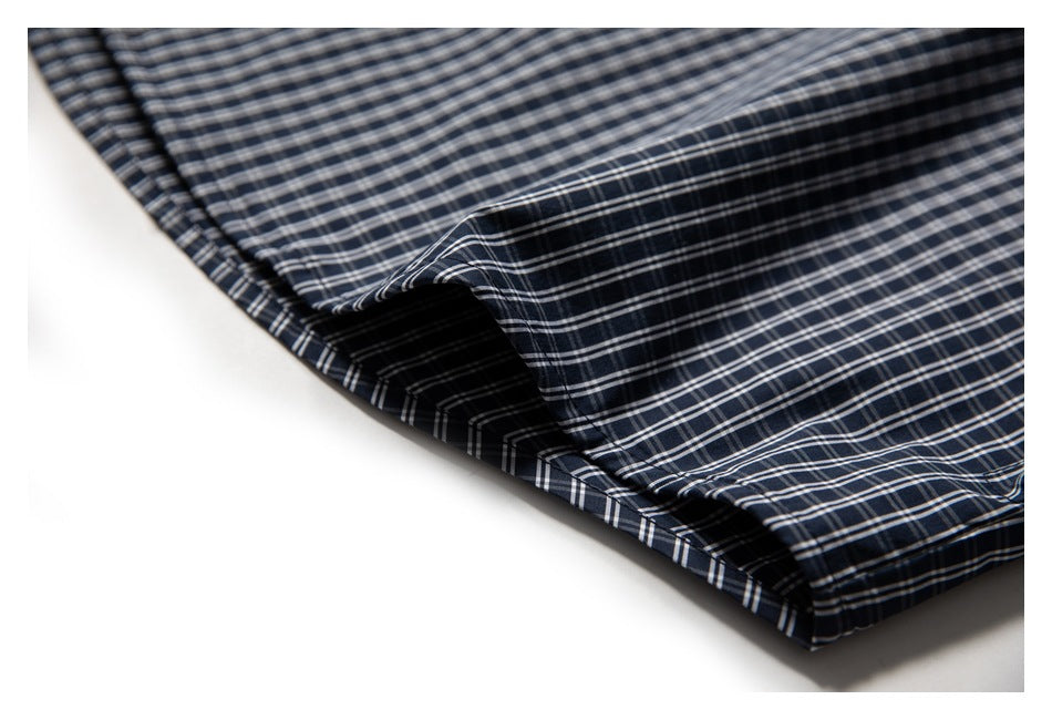 Close-up of the navy plaid shirt hem and stitched edge.