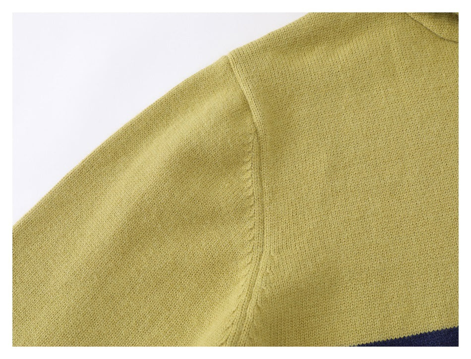 Close-up of the pale yellow-green knit fabric and shoulder seam, with a navy section visible at the edge.