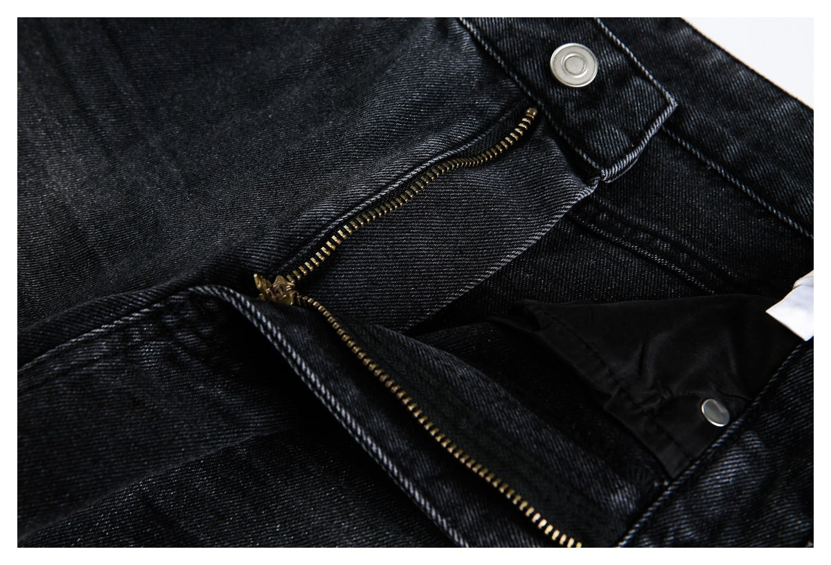 Close-up of the open zipper fly, metal button and inner facing of black jeans.