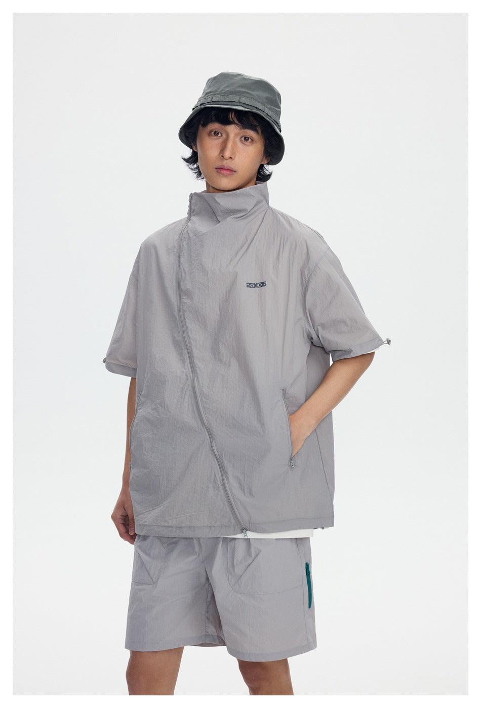 Front view of a model wearing a light gray short-sleeve jacket with a high collar and matching shorts.
