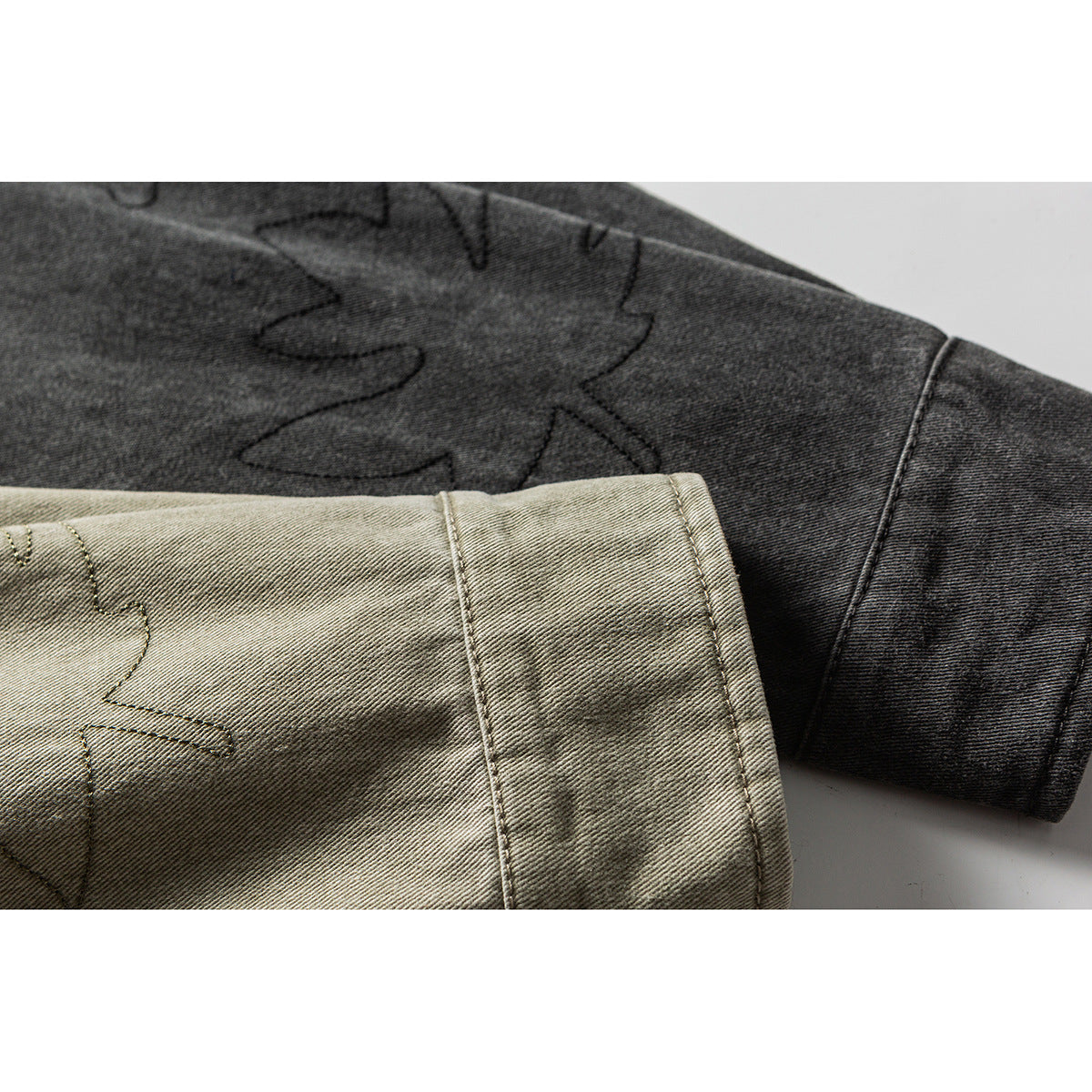 Close-up of olive-gray and charcoal shirt sleeves showing leaf outlines and stitched cuffs.