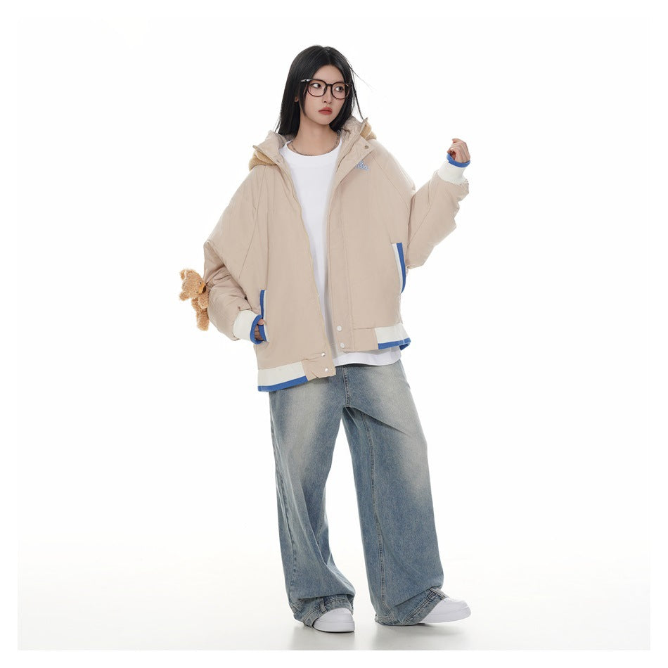 Full-length model wearing a beige jacket with a plush bear hood, blue-and-white trim, and wide-leg jeans.