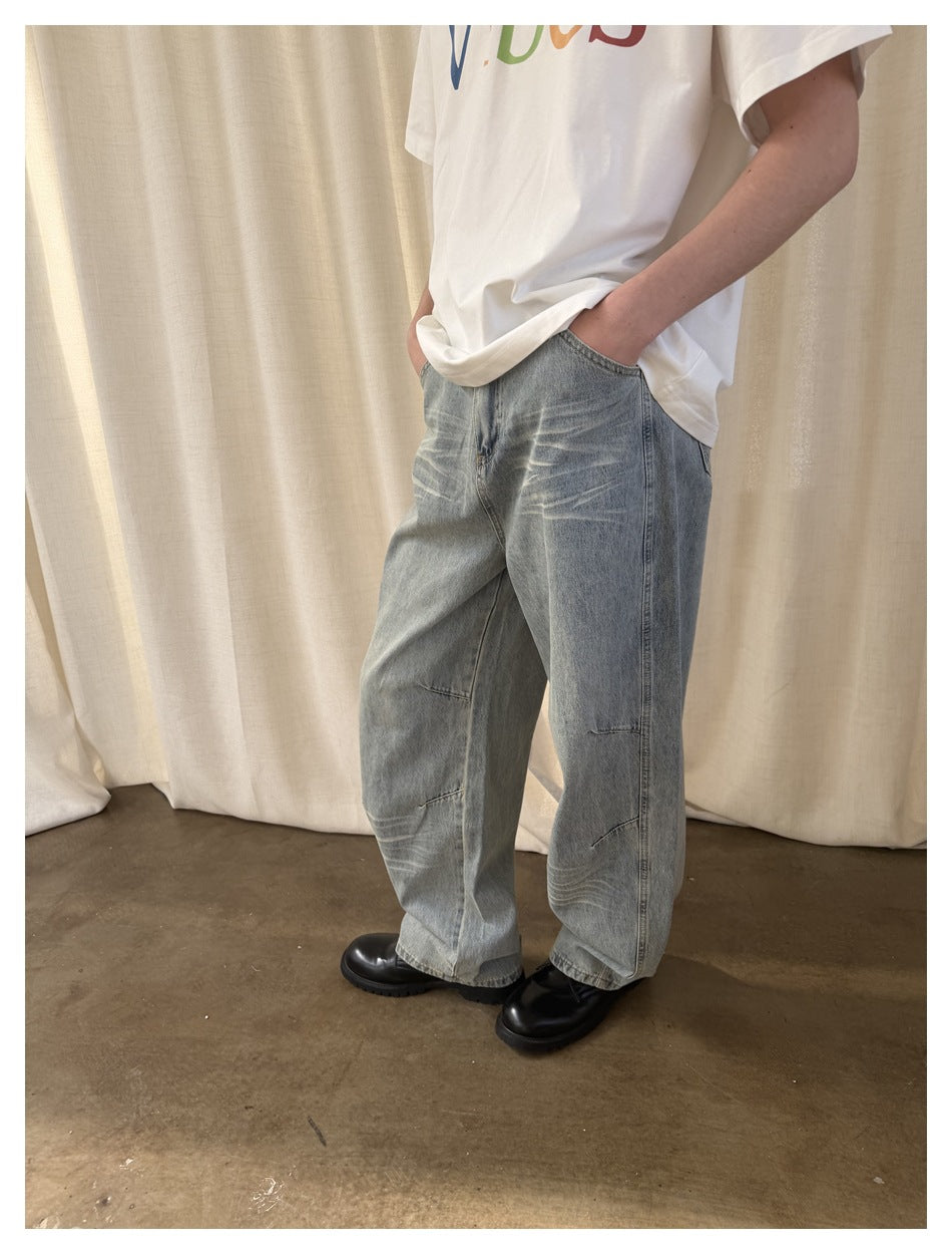 Person wearing loose, faded light-blue jeans with wide legs, shown from waist to shoes.