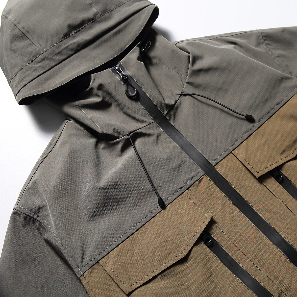 Close-up of a gray-and-tan hooded jacket showing the hood, drawcords, center zipper and flap pockets.