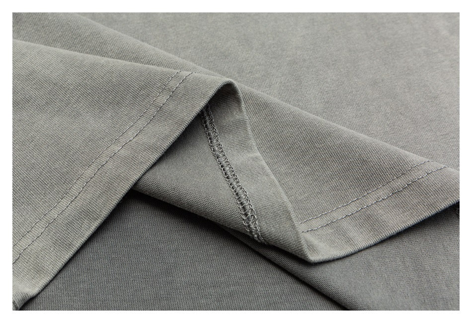 Close-up of a folded gray garment hem with parallel stitching and an overlocked edge.
